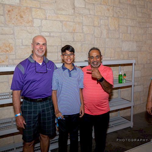 Four people posing, with three in front of an empty shelf and the fourth on the right. The photo is captioned 