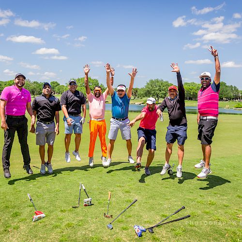 A group of seven people are jumping in the air on a golf course, with golf clubs lying on the grass in front of them.