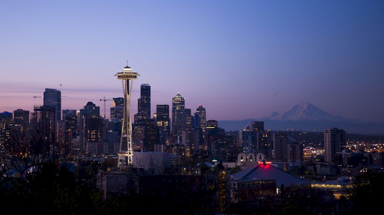 This image shows the Seattle skyline at dusk, featuring the Space Needle and various buildings, with Mount Rainier visible in the background.